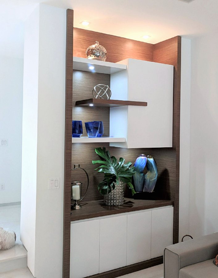Nicho con repisas iluminadas, gabinete blanco y fondo de madera