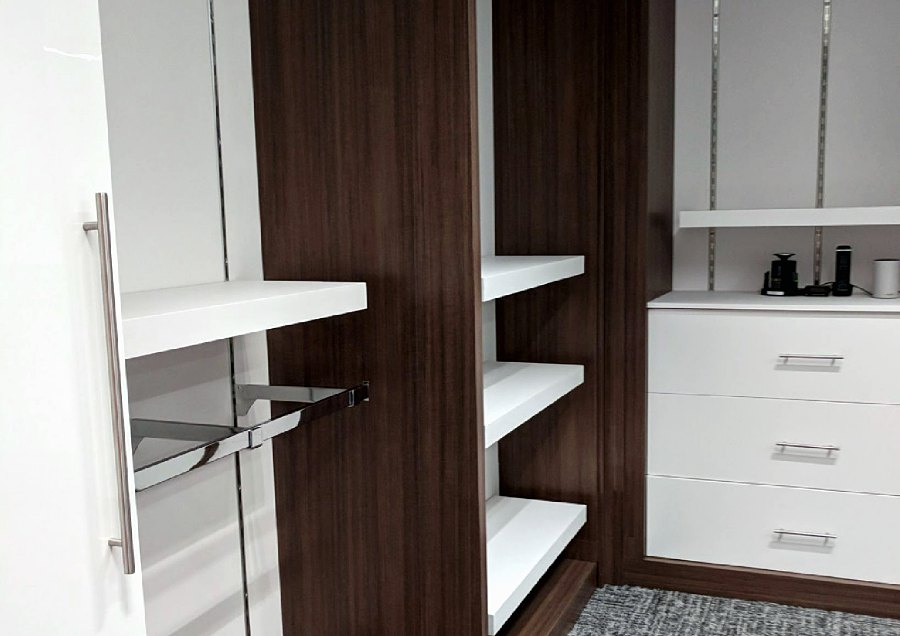 Storage detail with white shelves, hanging rail and drawers