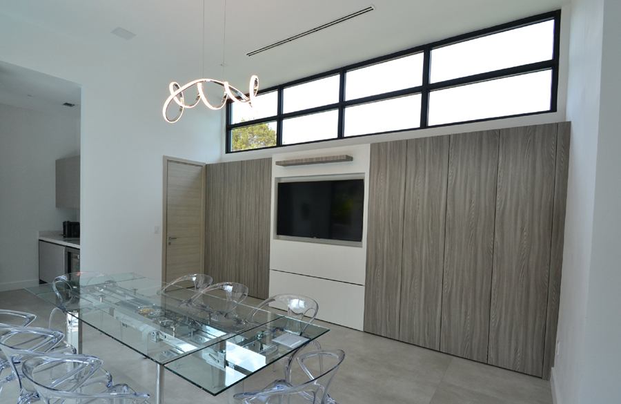 Floor-to-ceiling wood-grain storage wall with a built-in TV and a door
